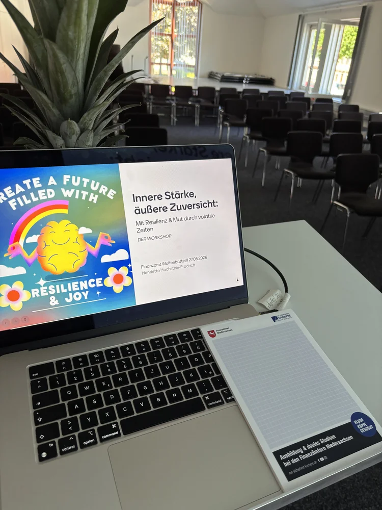 Laptop mit Titelfolie „Innere Stärke, äußere Zuversicht — Mit Resilienz & Mut durch volatile Zeiten“ im Workshop-Raum des Finanzamts Wolfenbüttel