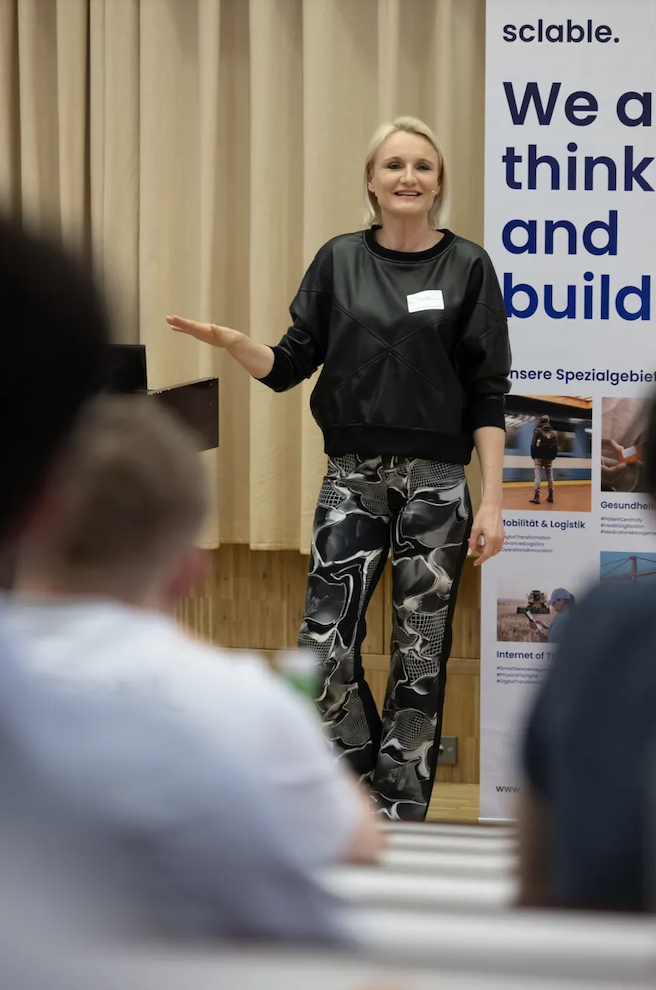 Henriette Frädrich auf der Bühne des Forum Produktion und Management 2025 der FH Oberösterreich, Campus Steyr, vor sclable-Banner „We think and build“